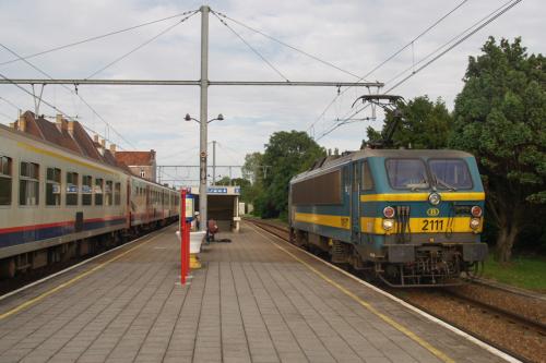 De loc 2111 is kop aan het maken te Adinkerke/De Panne.  Deze heeft er net een klein ritje naar de bundel opzitten. Hoewel we de frontseinen zien, rijdt de loc toch de andere kant op, om de overweg 2x te kruisen om zich vervolgens aan de andere kant van de sleep te plaatsen.